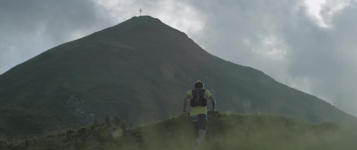 A man jogging up a large hill next to a mountain