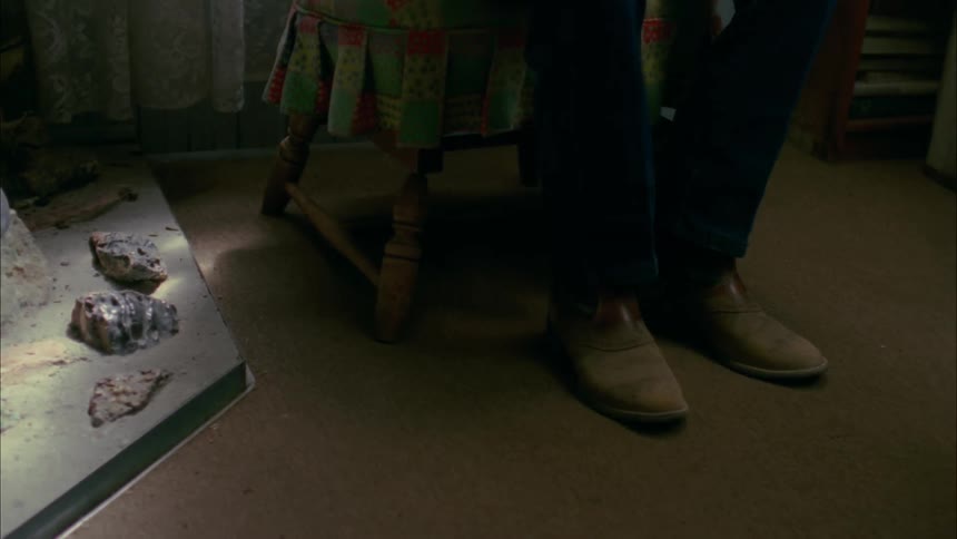 Boots of man sitting in chair in a house