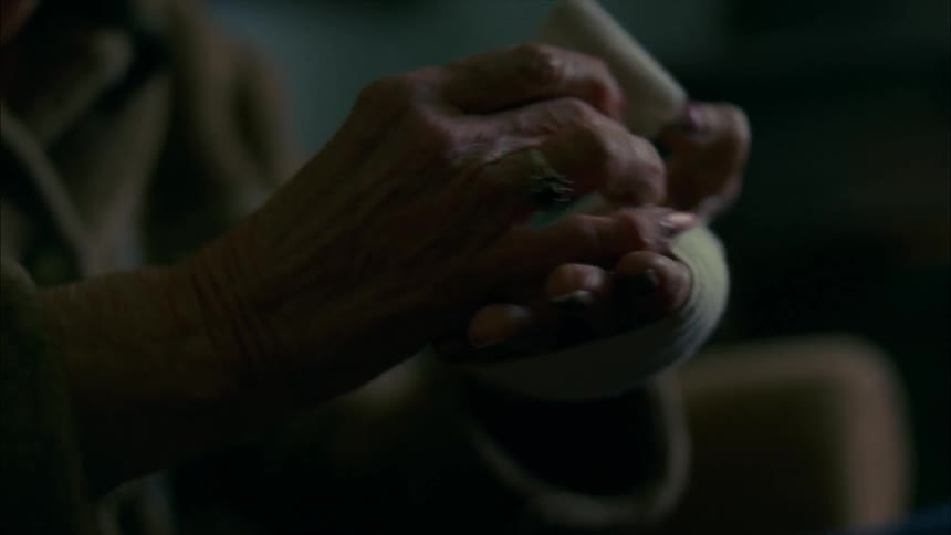Older woman sitting and wrapping her hand with elastic bandage