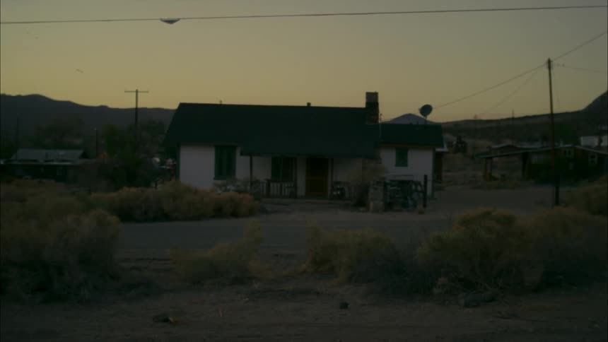 A house is surrounded by sagebrush in a rural area