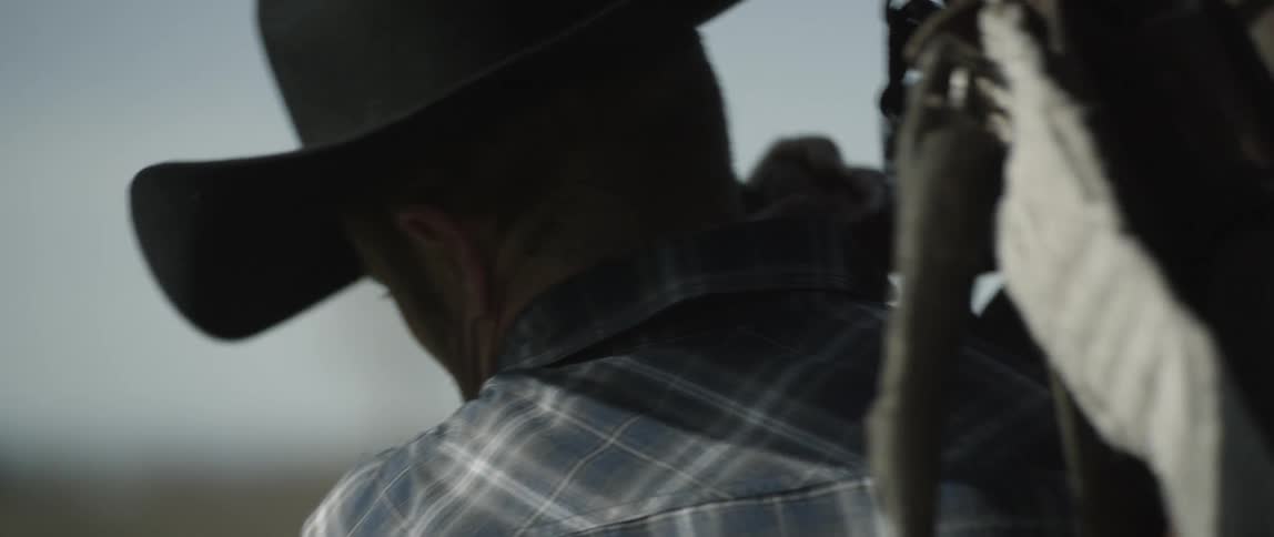 Cowboy lifting up his saddle to his shoulder