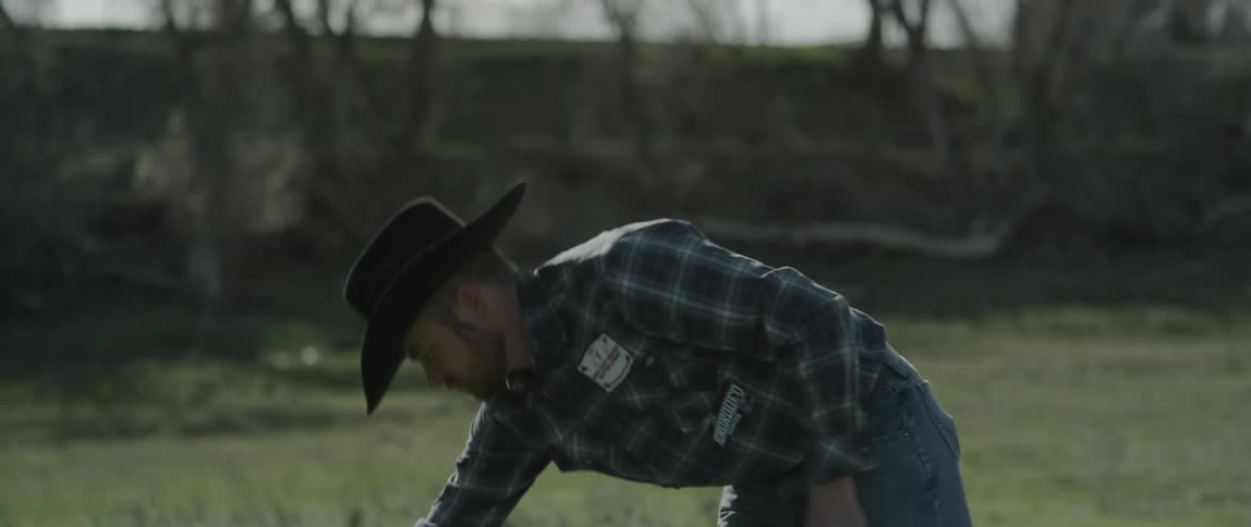 A man puts his saddle down on the grass