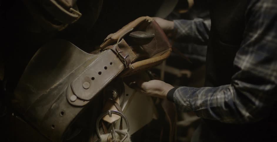 Man picking up a horse saddle