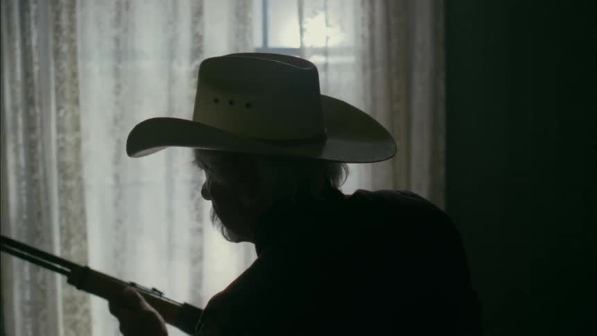 A man standing in front of a window examines a rifle