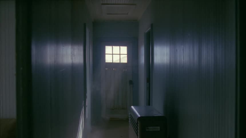 An elderly man wearing a cowboy hat enters the door of a house