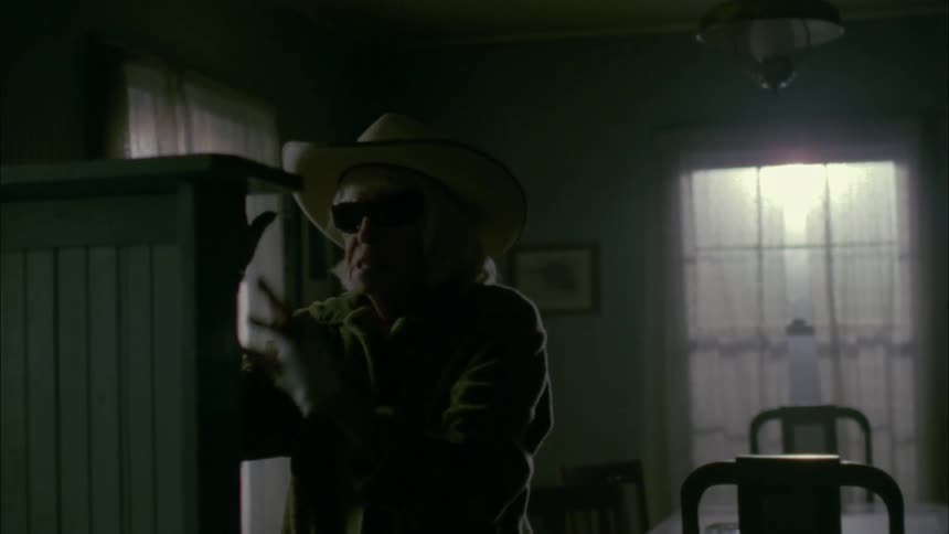 A blind woman in a hat walks around her dining room slowly