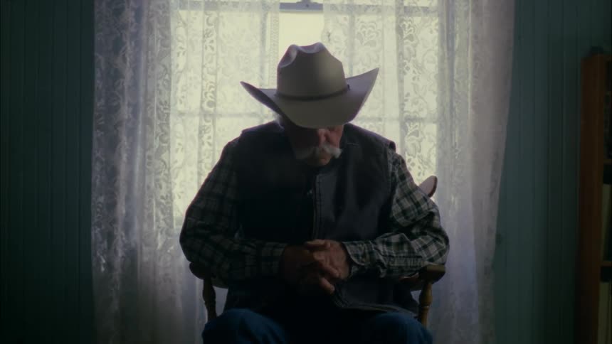 A man sleeps in a chair by the window