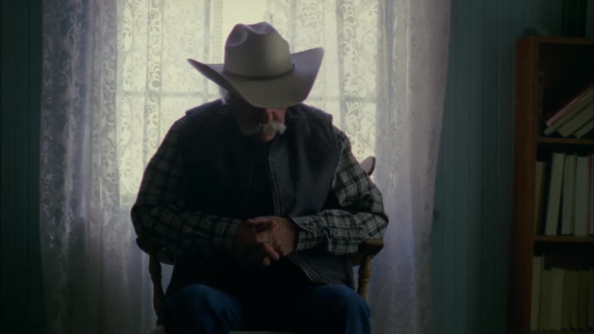 Older man sitting still in chair next to window