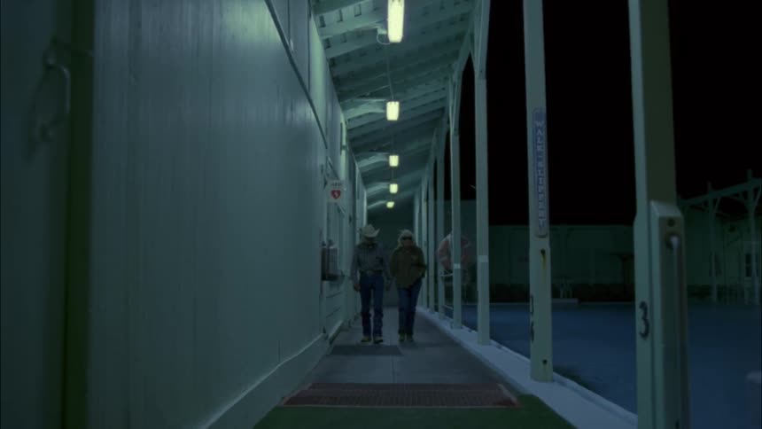 Elderly couple walks outside of an industrial building at night