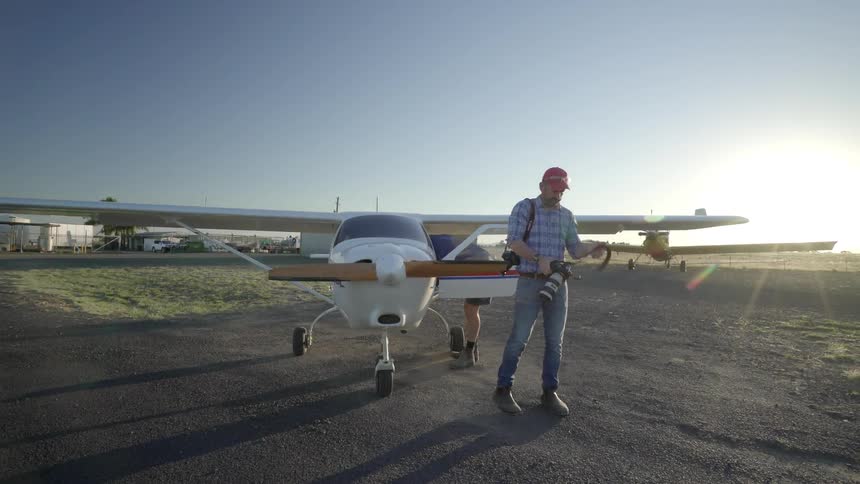 Two men stand near a small white plane
