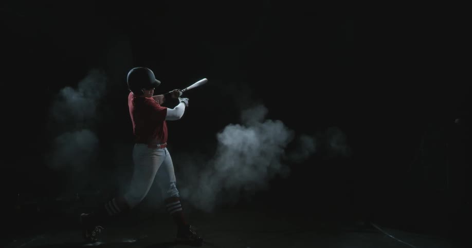Man connects with baseball using bat in dark area