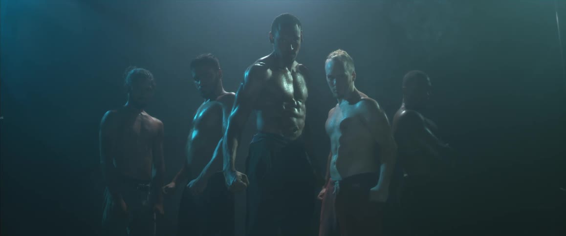 Row of men posing shirtless with their hands clenched