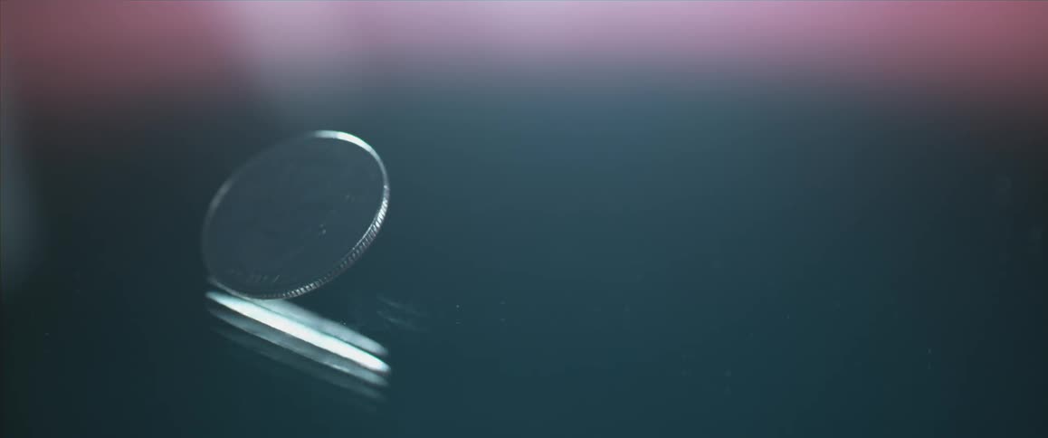 A quarter spins slowly on a reflective surface