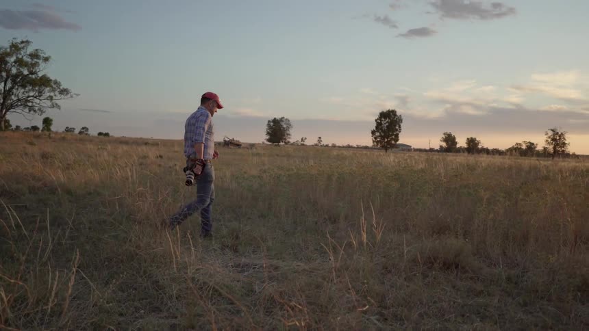 Man in field with camera photographing sunset