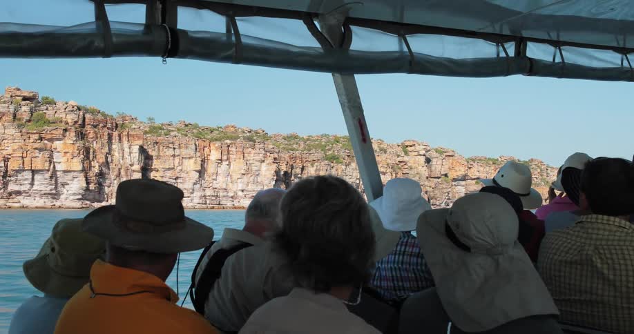 A boat full of tourists near a rocky shore