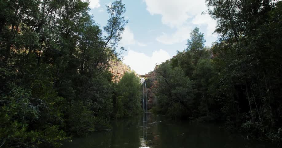 A waterfall flows over a cliff into the river below