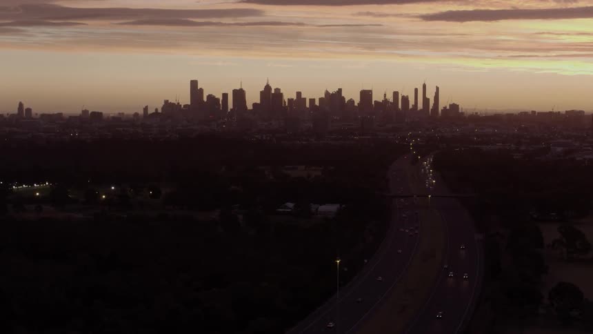 Cars drive on a city highway at sunset