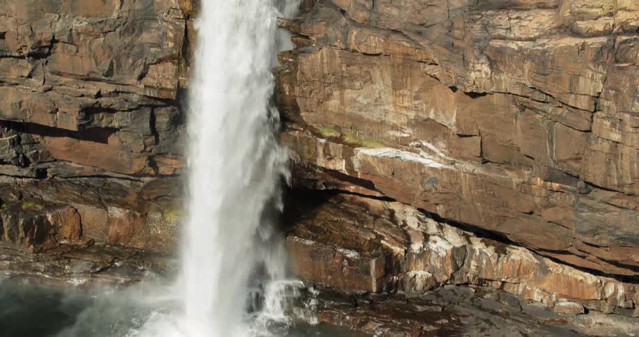 A waterfall gushes over a rocky cliff