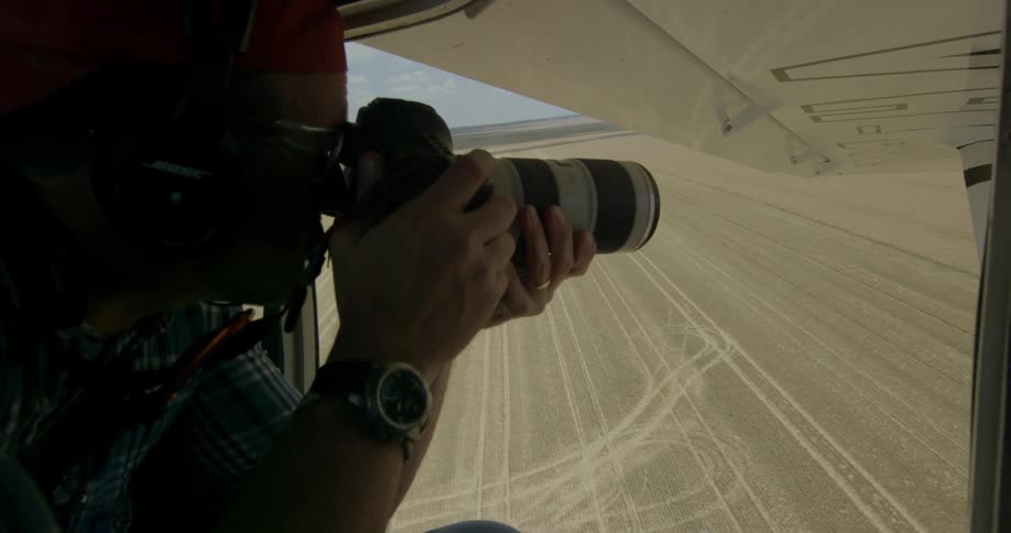 A man takes photographs from a small airplane