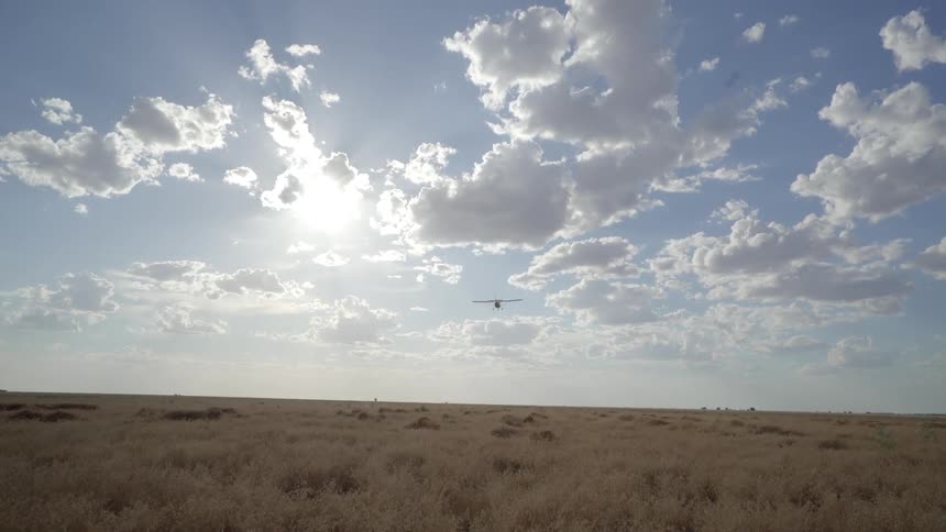 A plane flies over a long stretch of plains