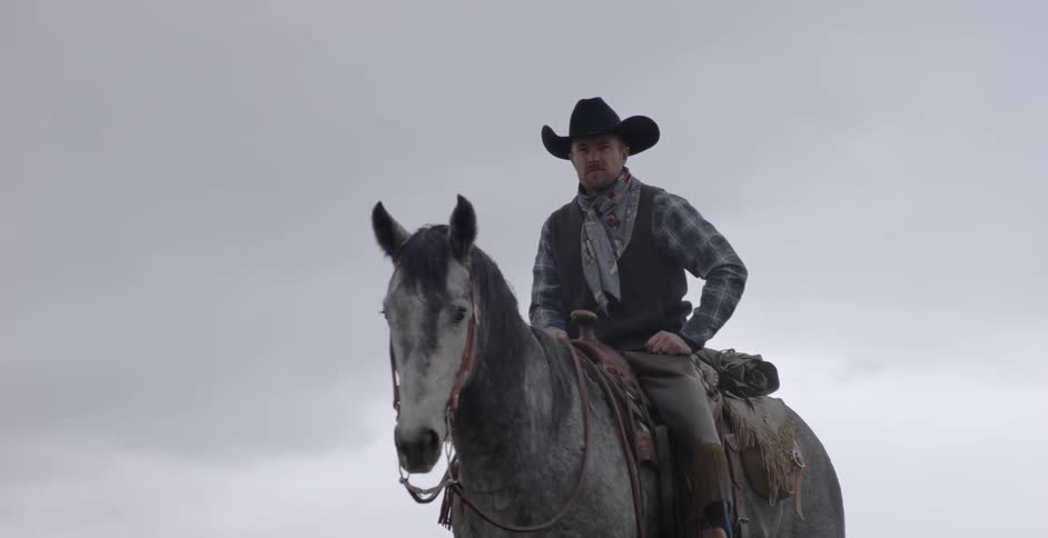 A man rides a horse while it's snowing