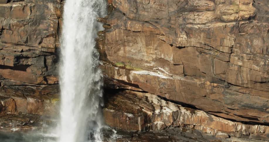A waterfall over a brown stone cliff