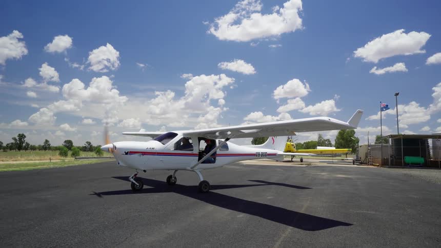 A small white plane travels down a runway