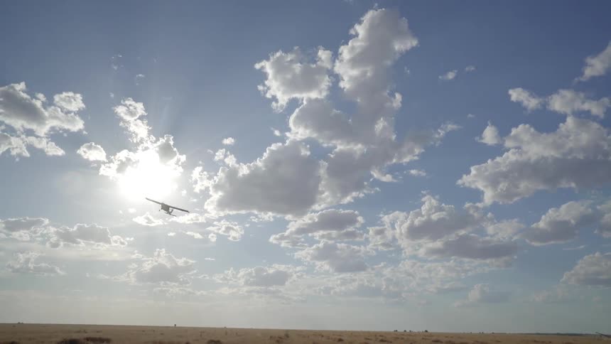 Airplane soars over a field on a sunny day