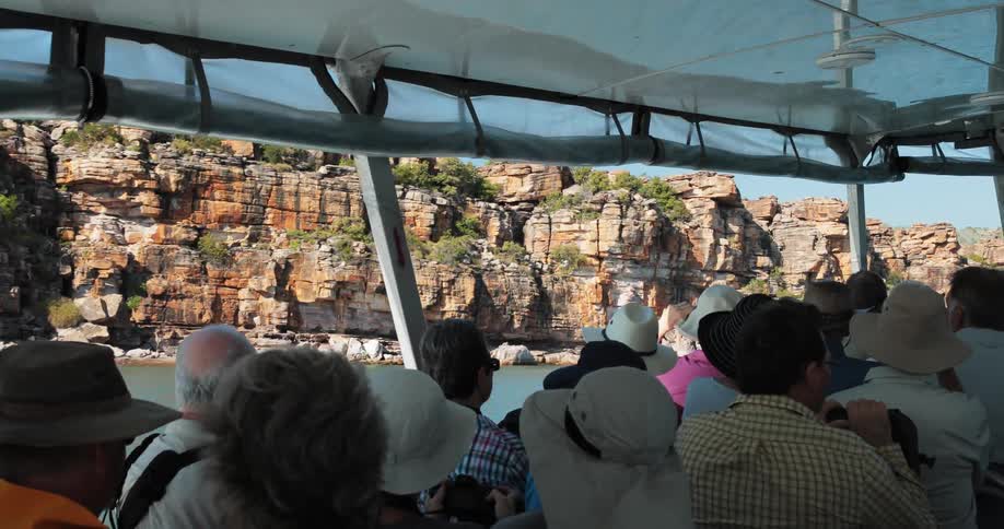 Group of tourists on a boat in the water traveling by cliffs