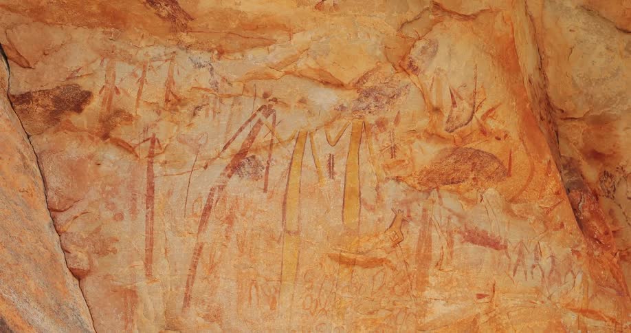 Paintings cover a red rock wall in the desert