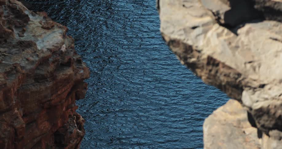 A body of water is being filmed from between two rocks