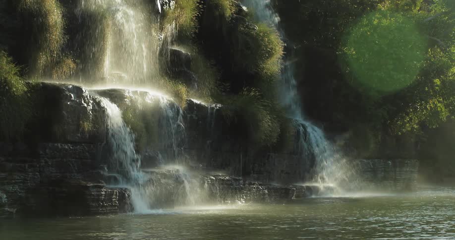 Water falls off the side of a cliff into a stream