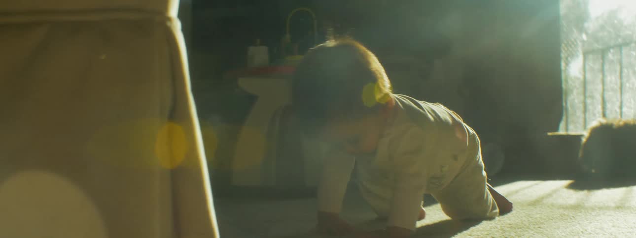 A baby crawls toward a chair