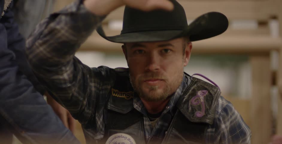 Man wearing a cowboy hat nods and looks down