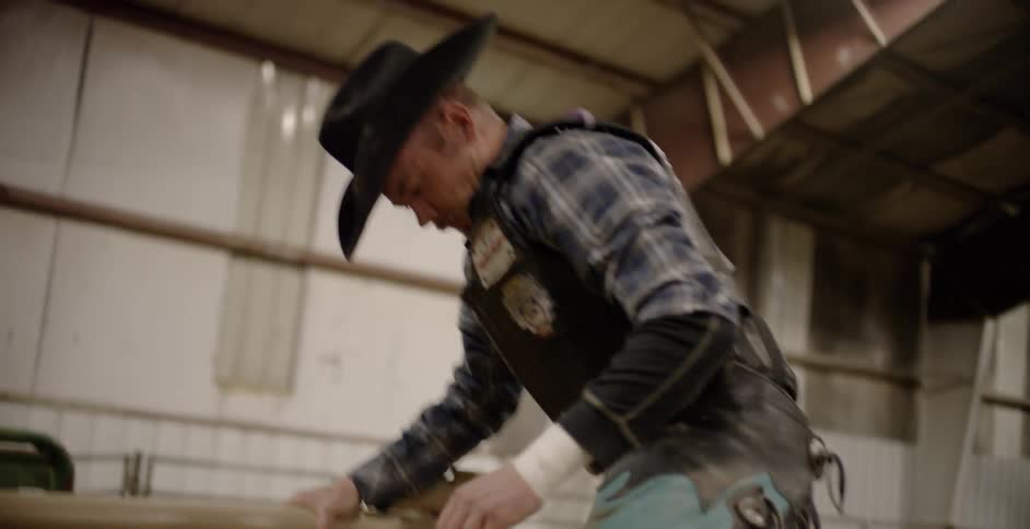 A cowboy climbs into a bullpen