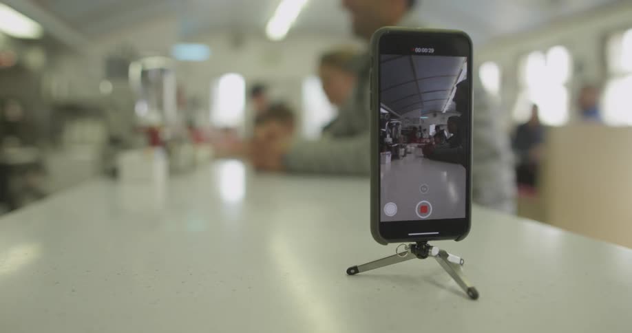 Phone on a small stand records people sitting at a long counter
