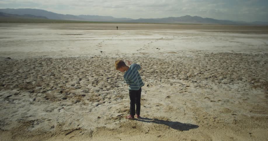A boy is standing in the desert