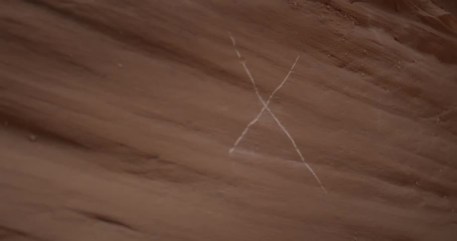 The letter x carved into a rock wall