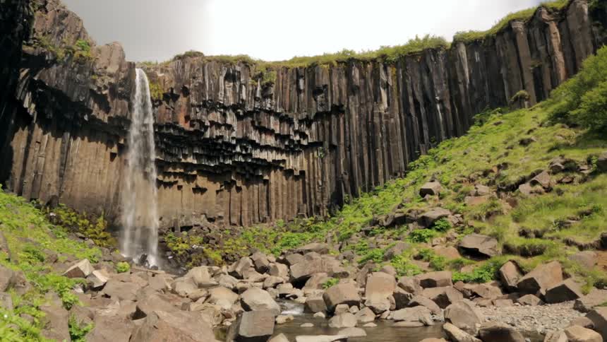 A waterfall flows over a rocky cliff