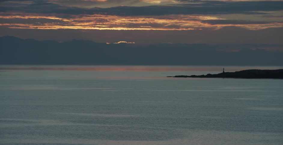 Small waves ripple in the water below a sunset