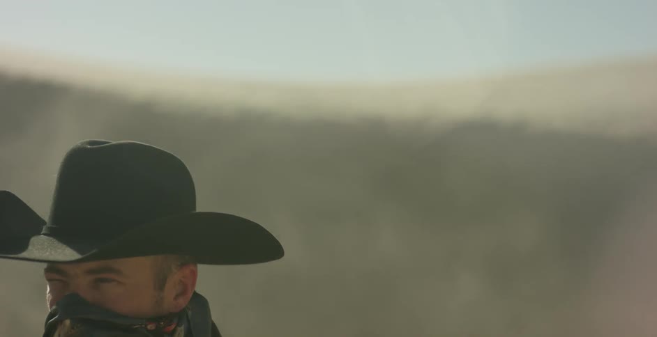 Dust flies around a cowboy in a desert