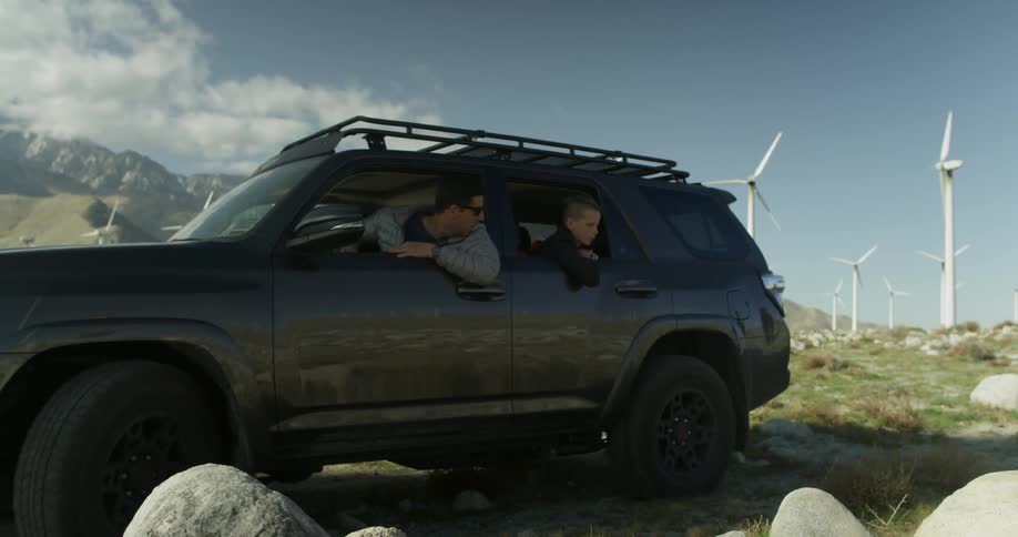 A man backs up a car near wind turbines
