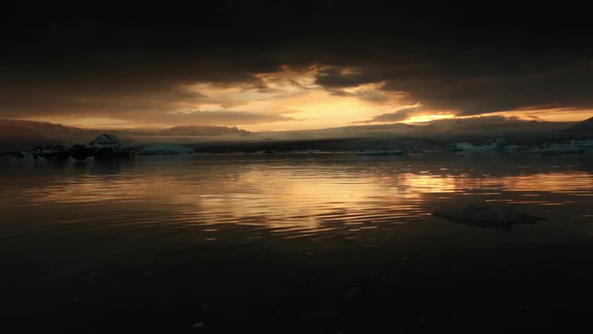 Water flows under clouds and the setting sun