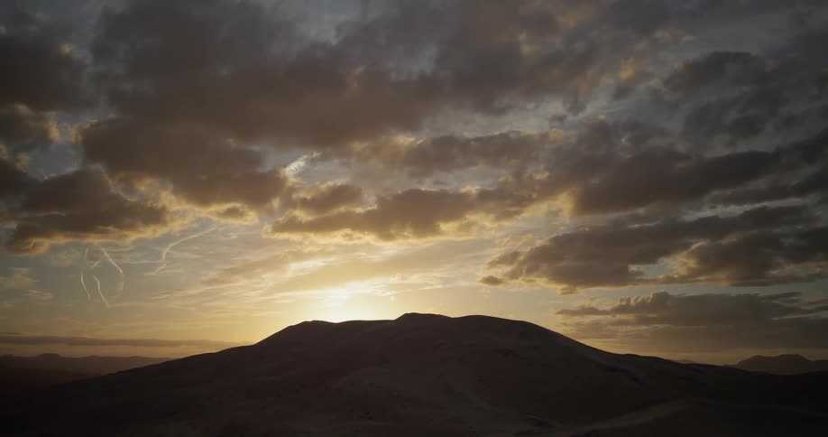 The sun sets behind a mountain