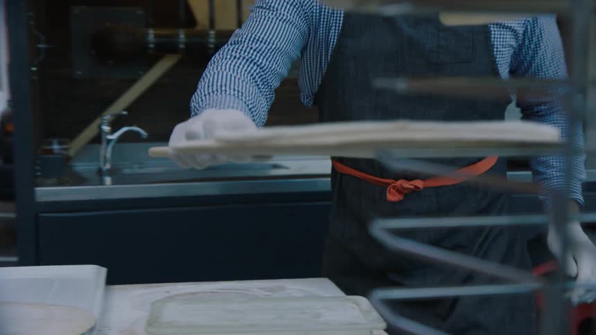 A restaurant worker prepares pizza dough