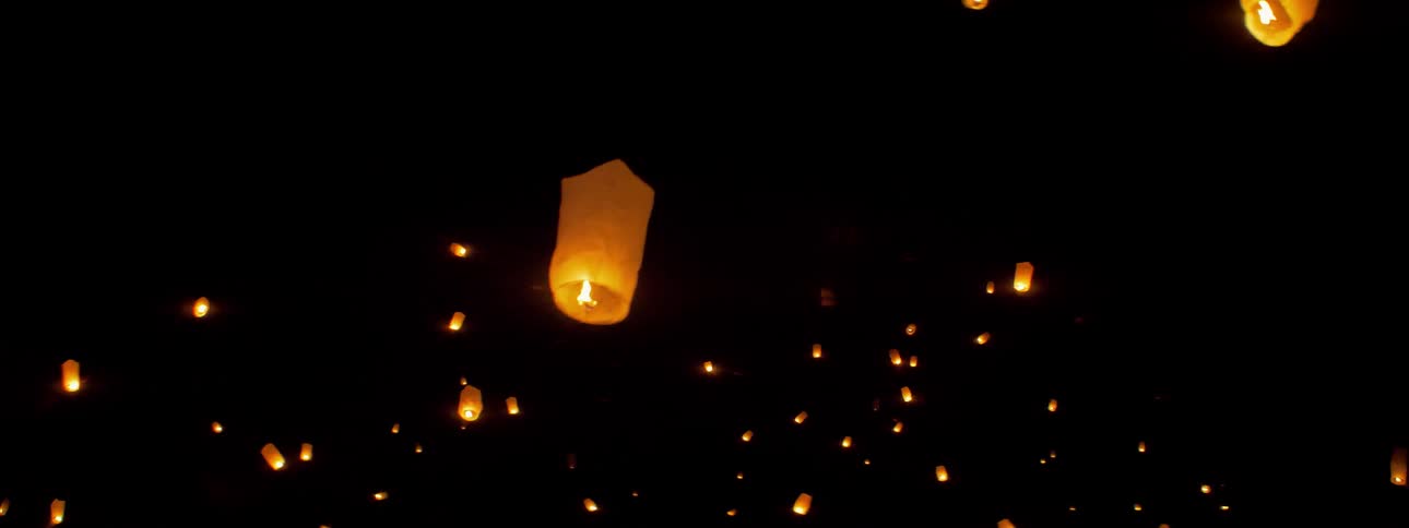 A lot of bags with candles in them flying in the air