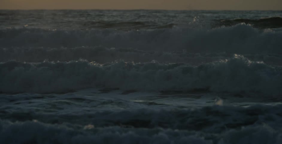 Ocean waves splashing to shore at sunset