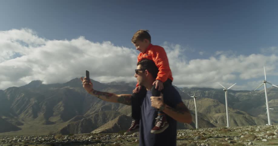A man takes a selfie of himself with his son on his shoulders