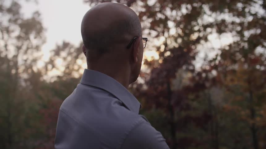 A man looks at fall trees at sunset