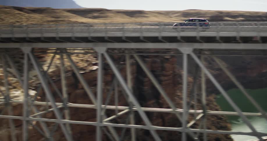 Car driving on high bridge over river on sunny day
